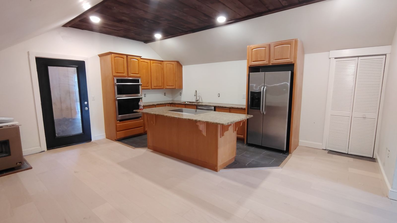 Finished kitchen with wood cabinets, a granite island, and stainless appliances
