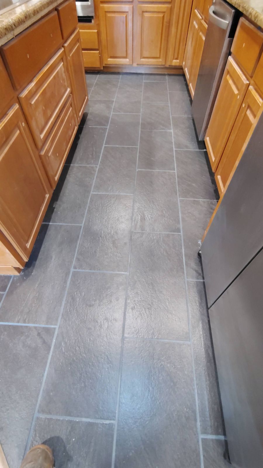 Dark slate-look tile floor between kitchen cabinets