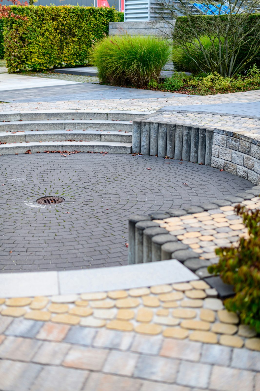 Sunken circular paver patio with curved stone steps and a low block wall