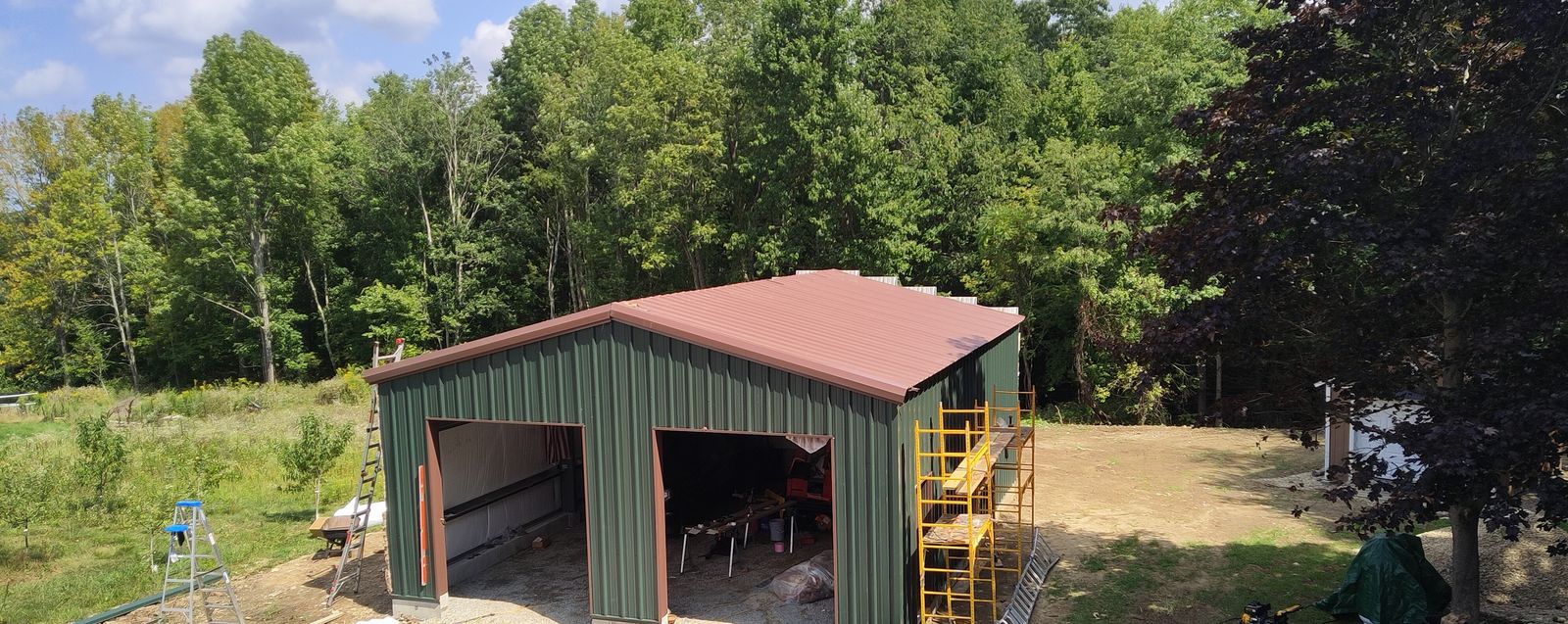 Green metal garage with two bay openings and a brown roof