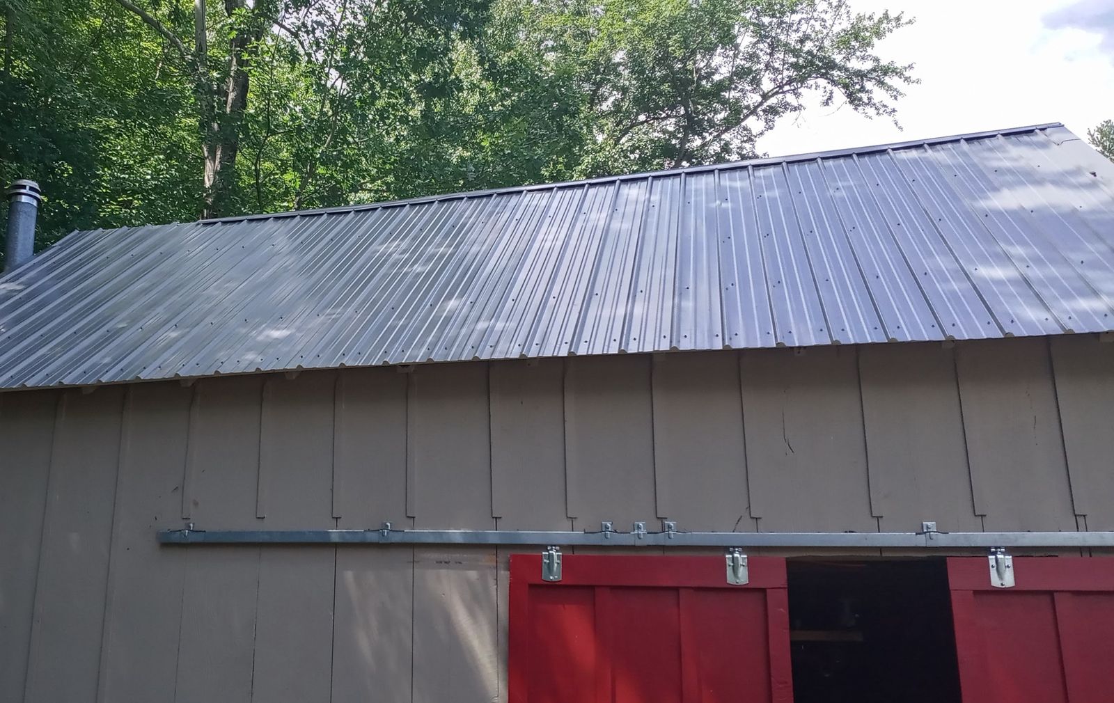 New metal roof on a barn with red sliding doors