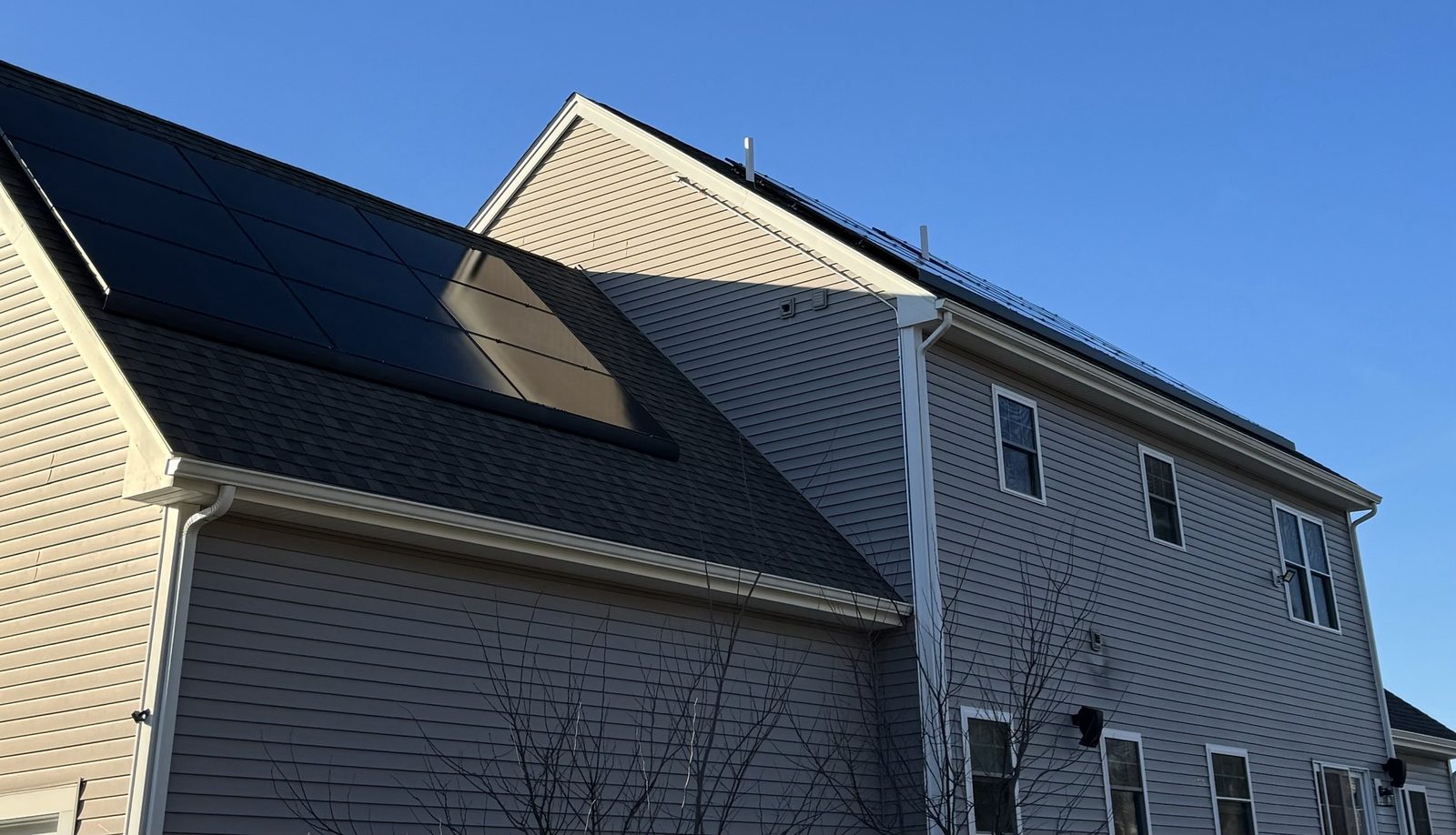 Black solar panels on two roof sections of a two-story home