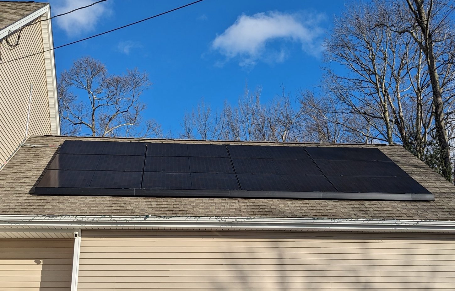Black solar panels covering a garage roof under a blue sky