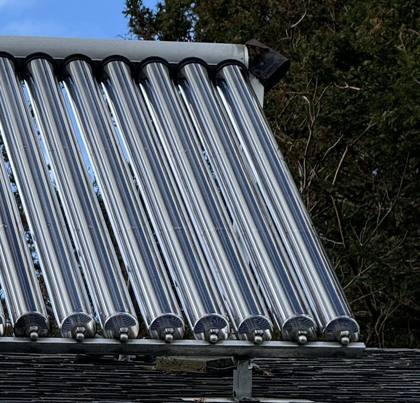 Row of evacuated solar hot water tubes mounted on a shingle roof