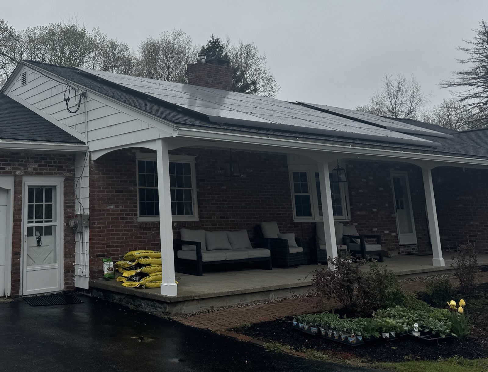 Solar panels on the roof of a brick ranch house with a front porch