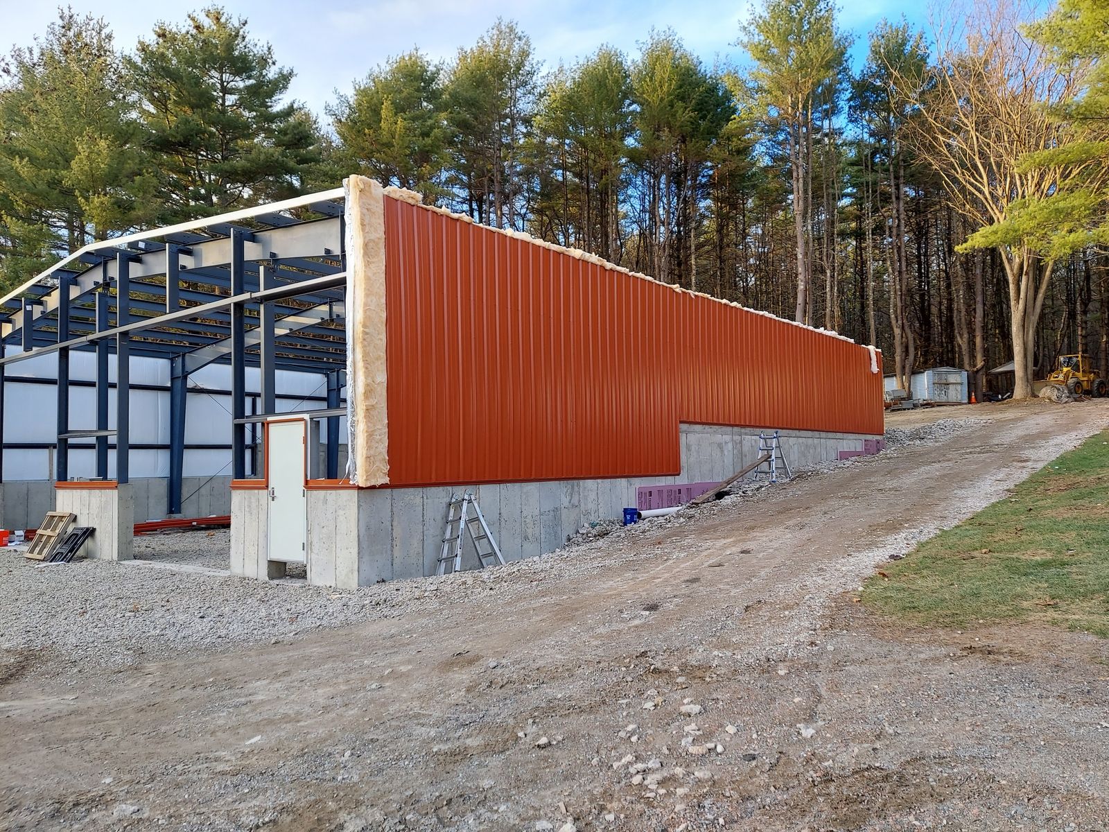 Steel-frame building with orange metal wall panels on a concrete foundation