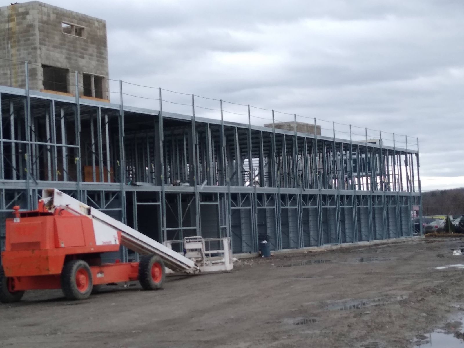 Long two-story steel-framed building with a boom lift in front