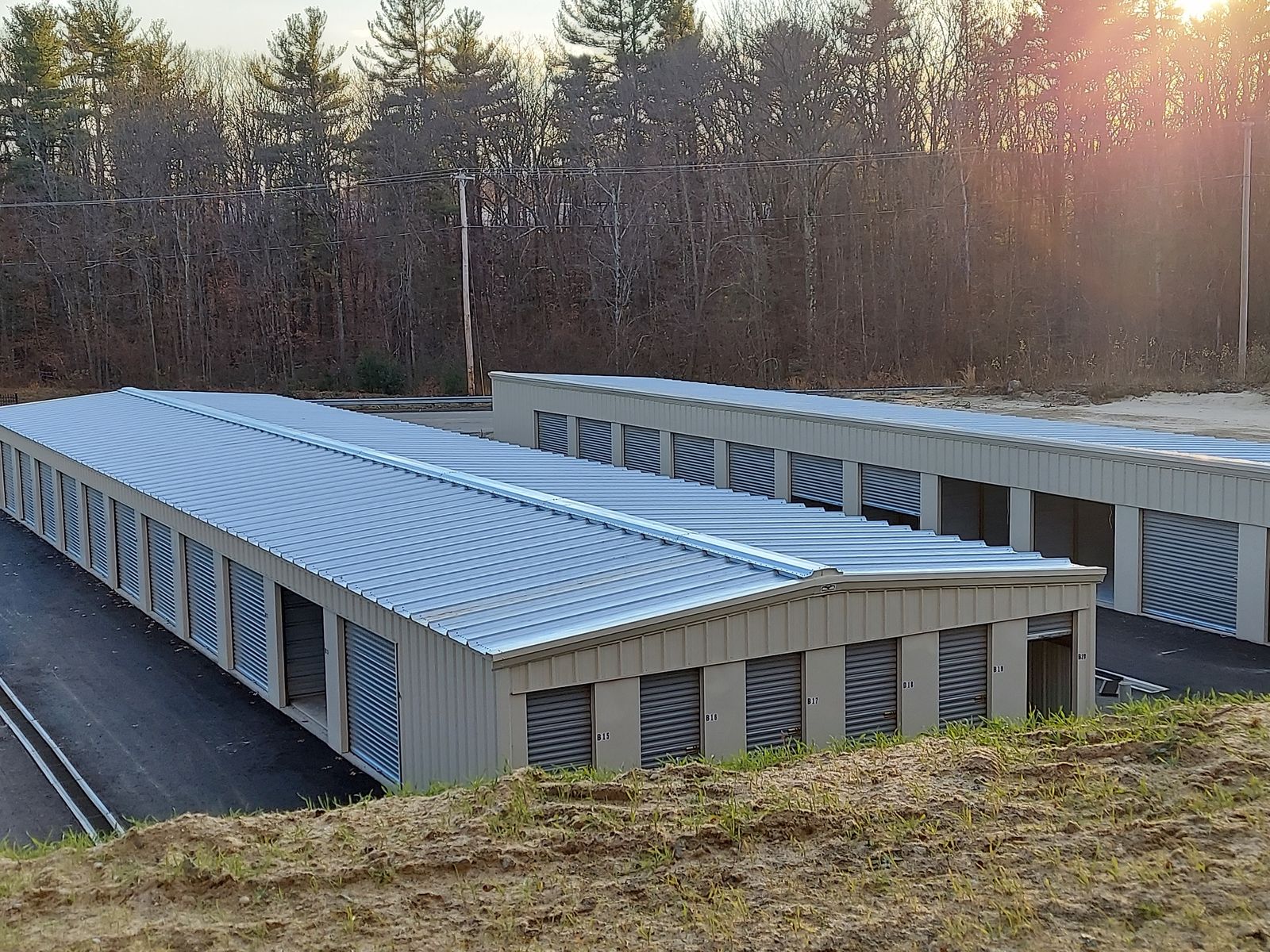 Two finished self-storage buildings with metal roofs and roll-up doors