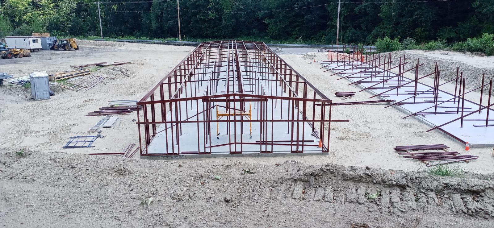 Steel frame of a long storage building standing on a concrete slab