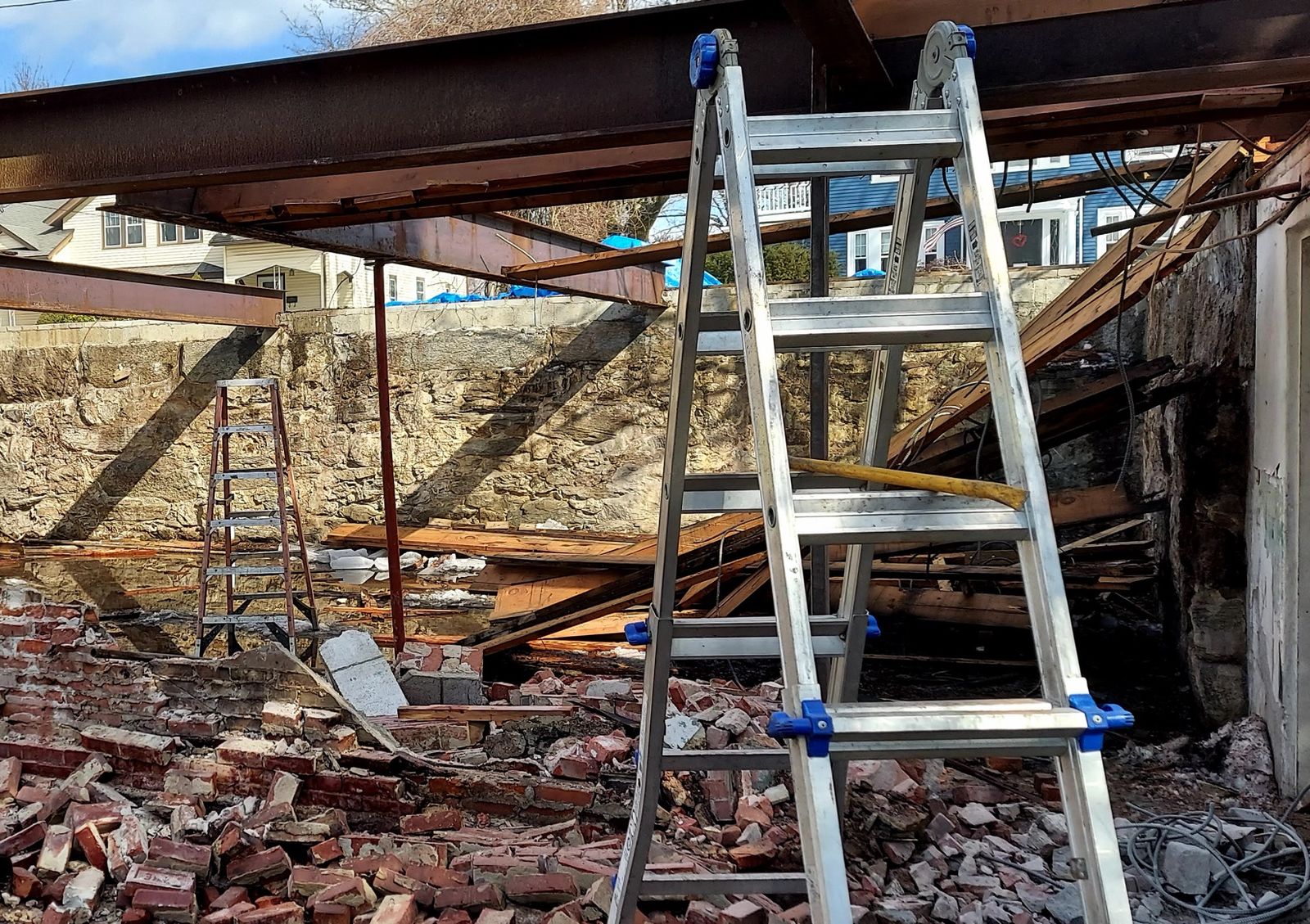 Steel beams spanning an old stone and brick foundation during a rebuild