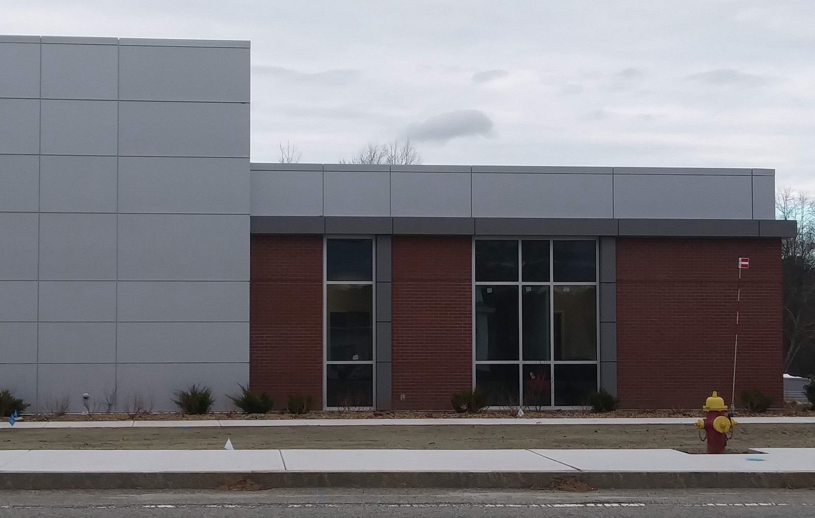 Commercial building finished with gray metal wall panels and brick