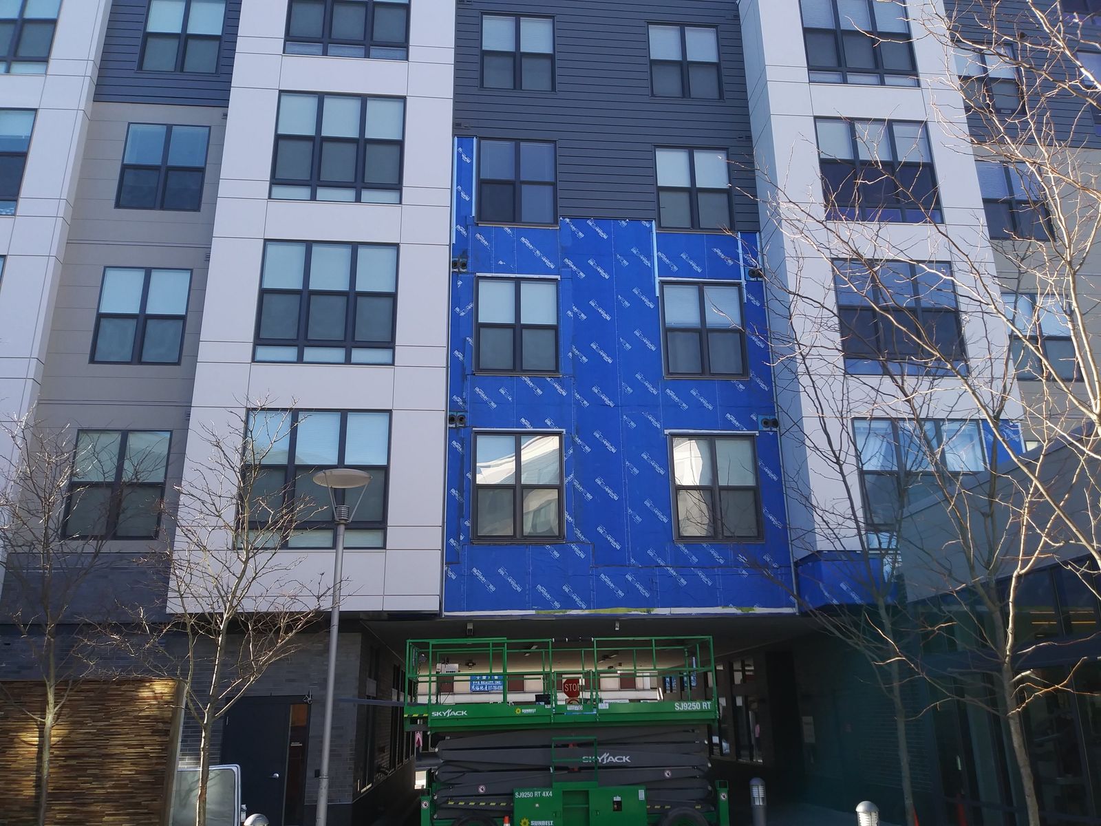 Apartment building wall covered in blue weather barrier, ready for siding